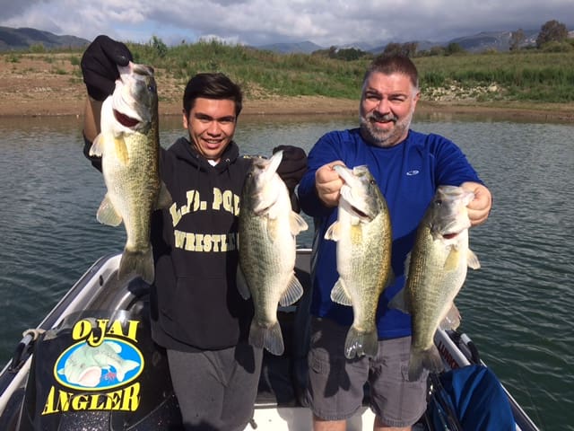 Two men holding up large fish on a boat.