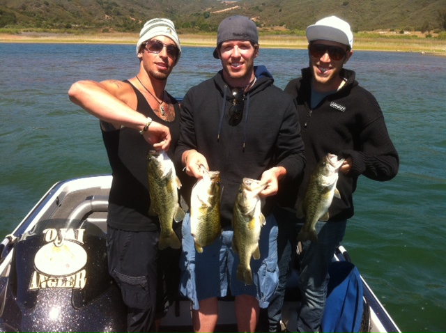 Three men holding up fish on a boat.