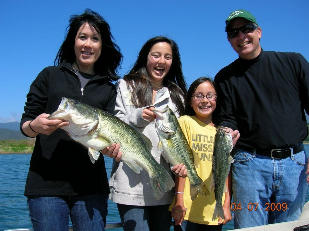 A family holding two fish while standing on the beach.
