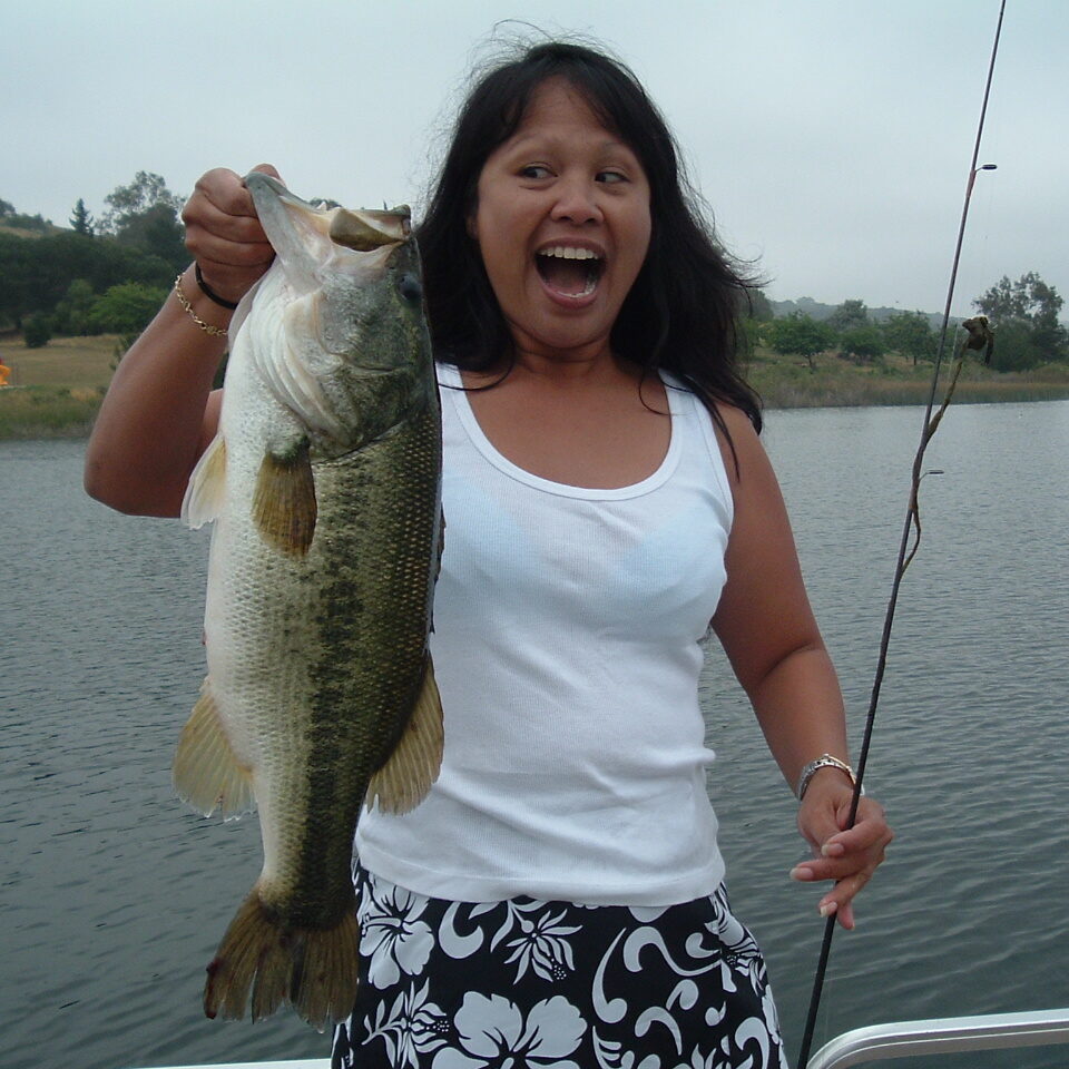 A woman holding a large fish on top of a boat.