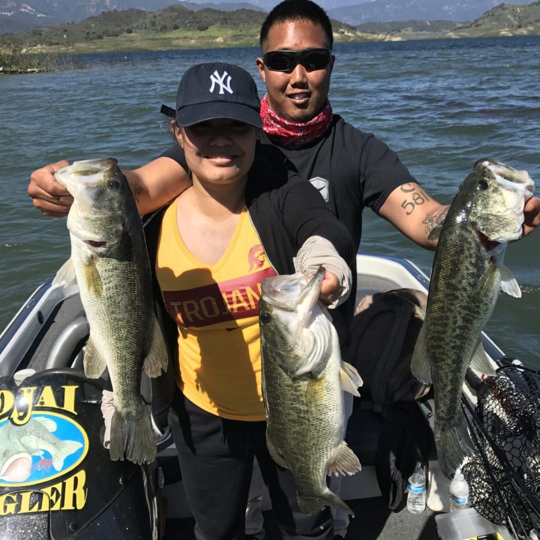 A man and woman holding two fish on the boat.