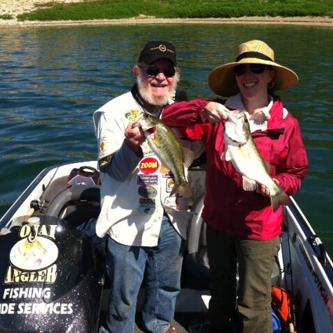 A man and woman holding fish on the side of a boat.